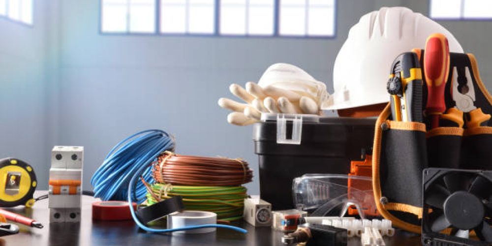 Composition with tools and electrical equipment on black table and industrial ship background. Horizontal composition. Front view.